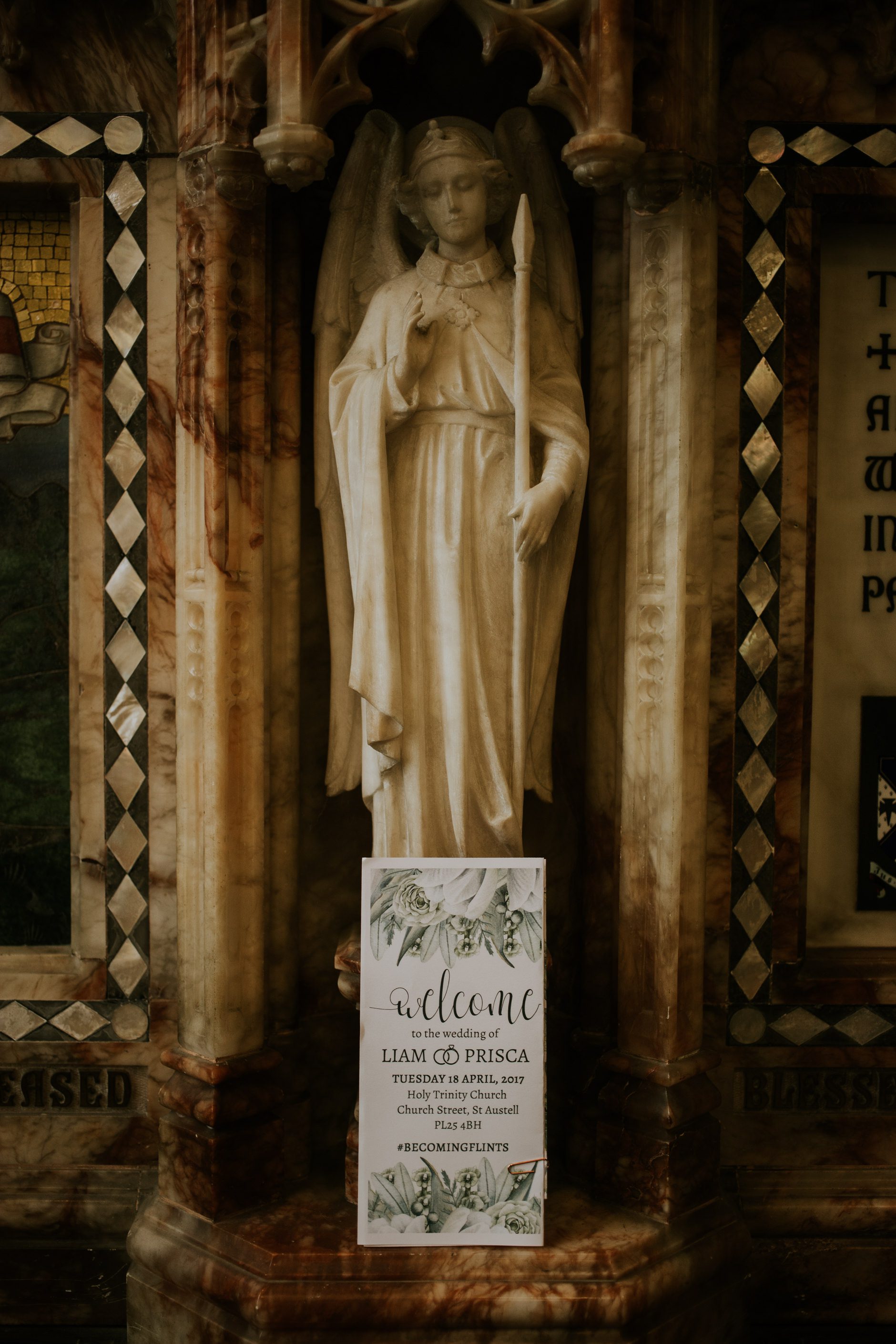 Wedding invitation detail under a carved statue in a church