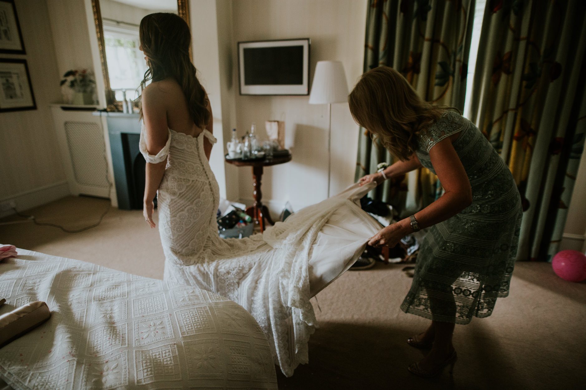 The brise's mother helps her with her wedding dress