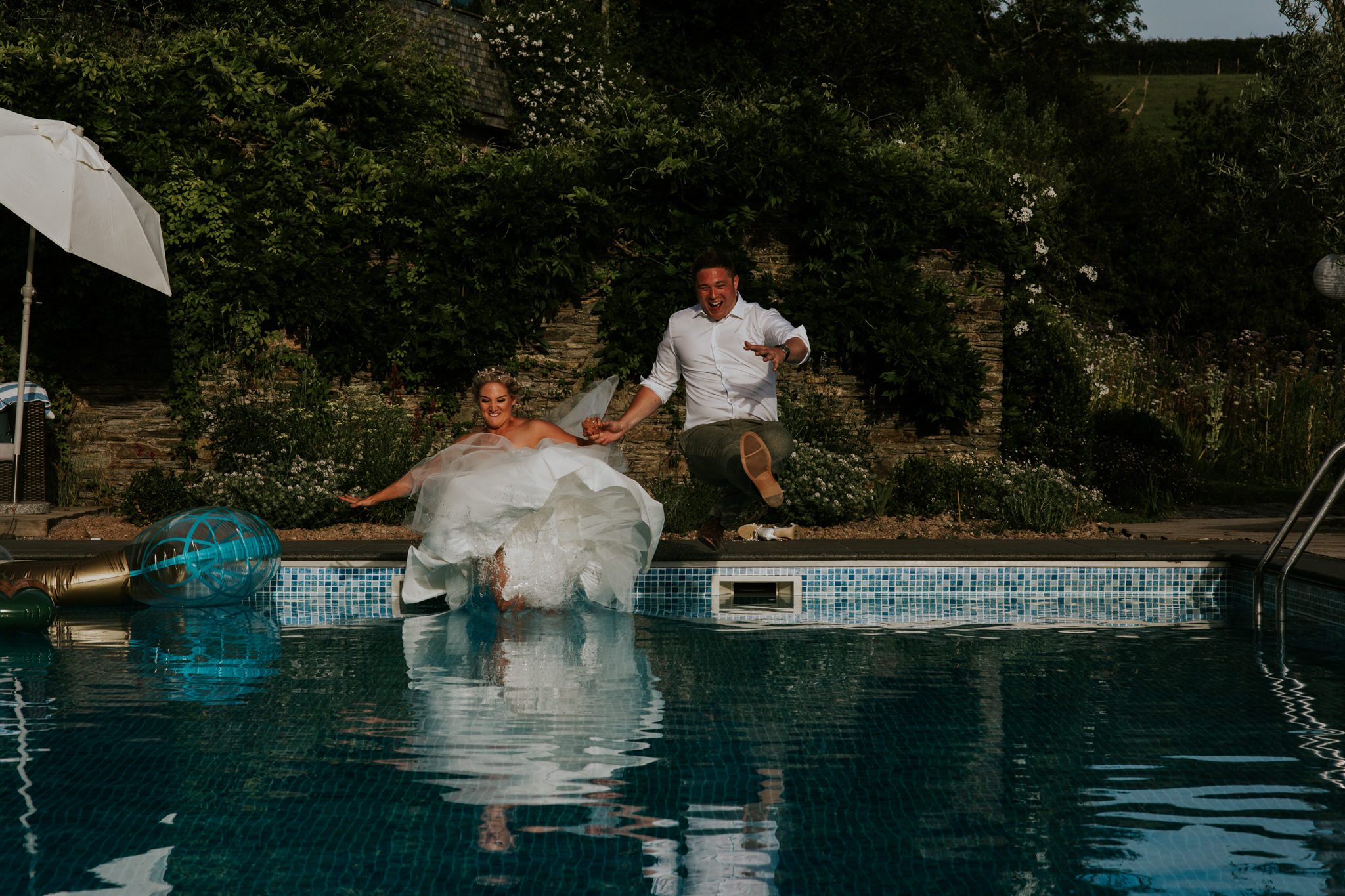 Bride and groom jimp into swimming pool after their wedding