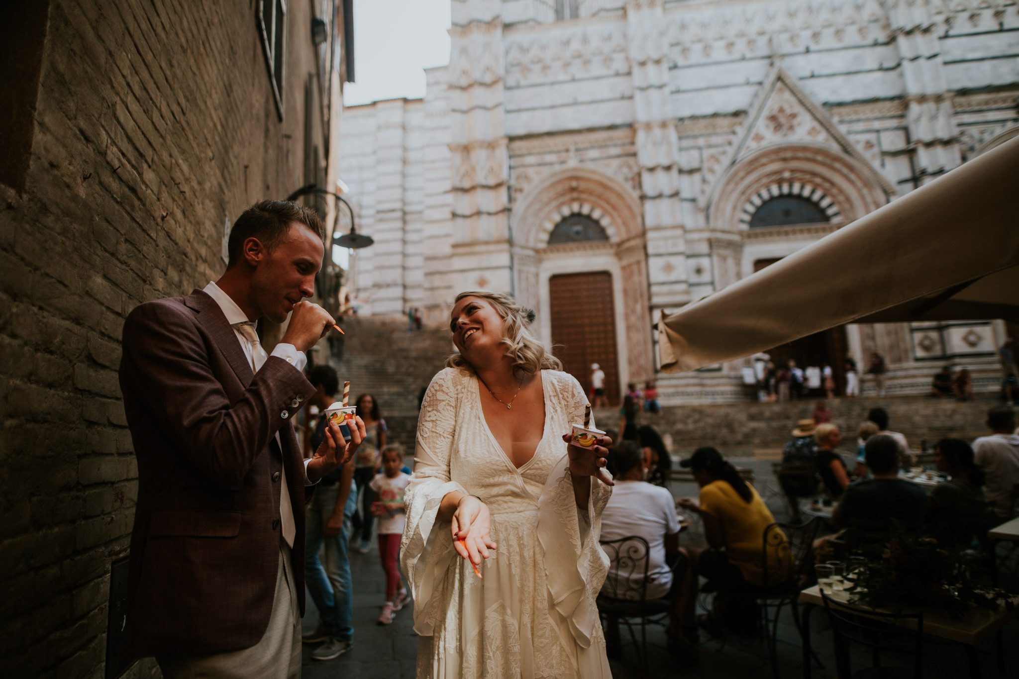 A bride and groom eat ice cream together in Siena, Tuscany, Italy