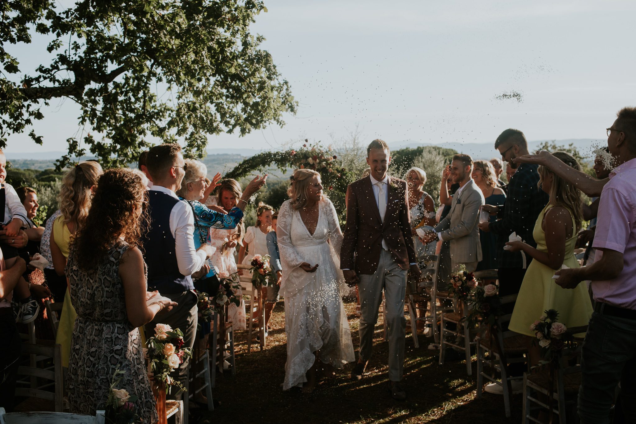 Bride and groom walk through confetti at their Tuscan wedding