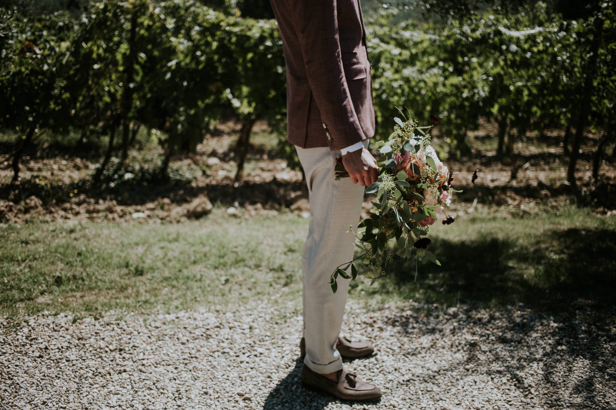 Groom waits for bride with flowers in his hand before his wedding ceremony at Fattoria di Corsigano near Siena in Tuscany, Italy