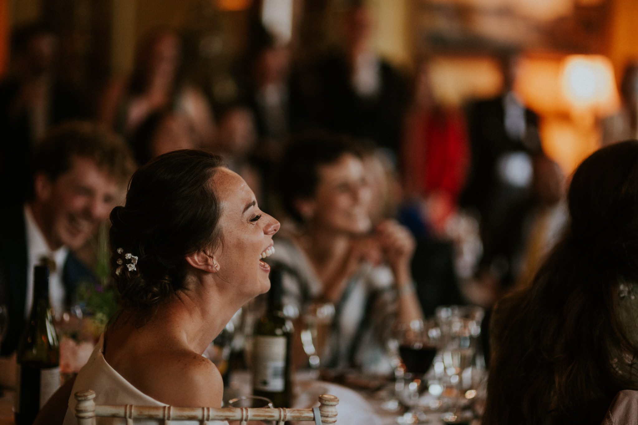 A happy bride laughs during wedding speeches