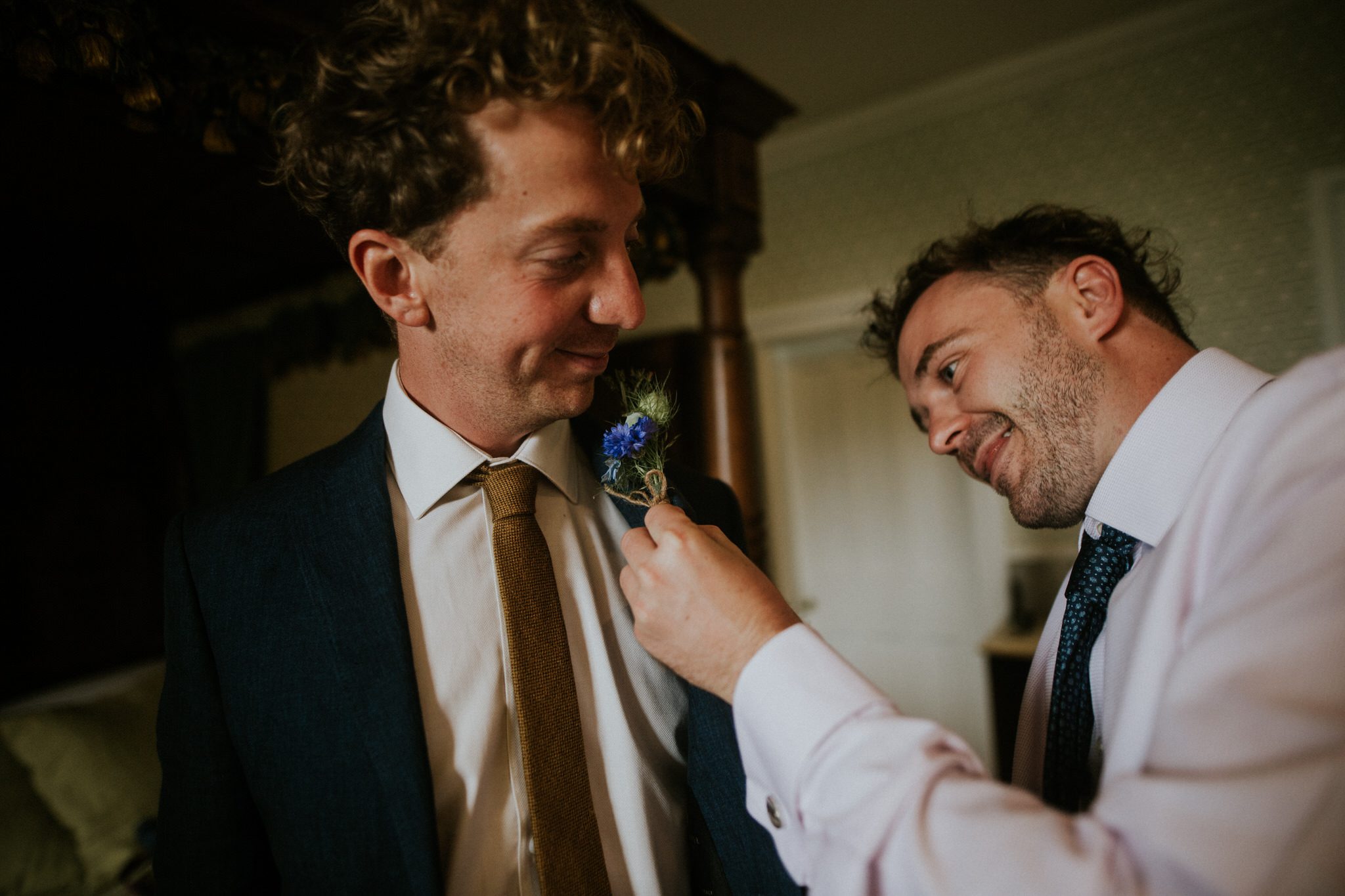 The best man pins a button hole to the groom at Huntsham Court