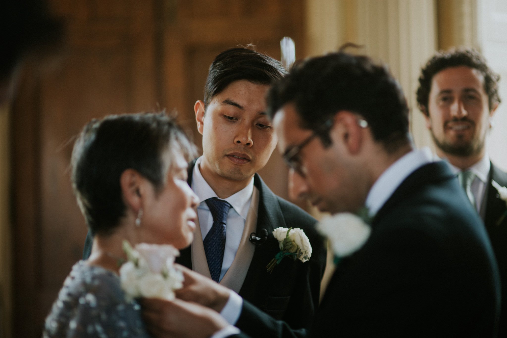 A groomsman pins a corsage to the dress of the groom's mother