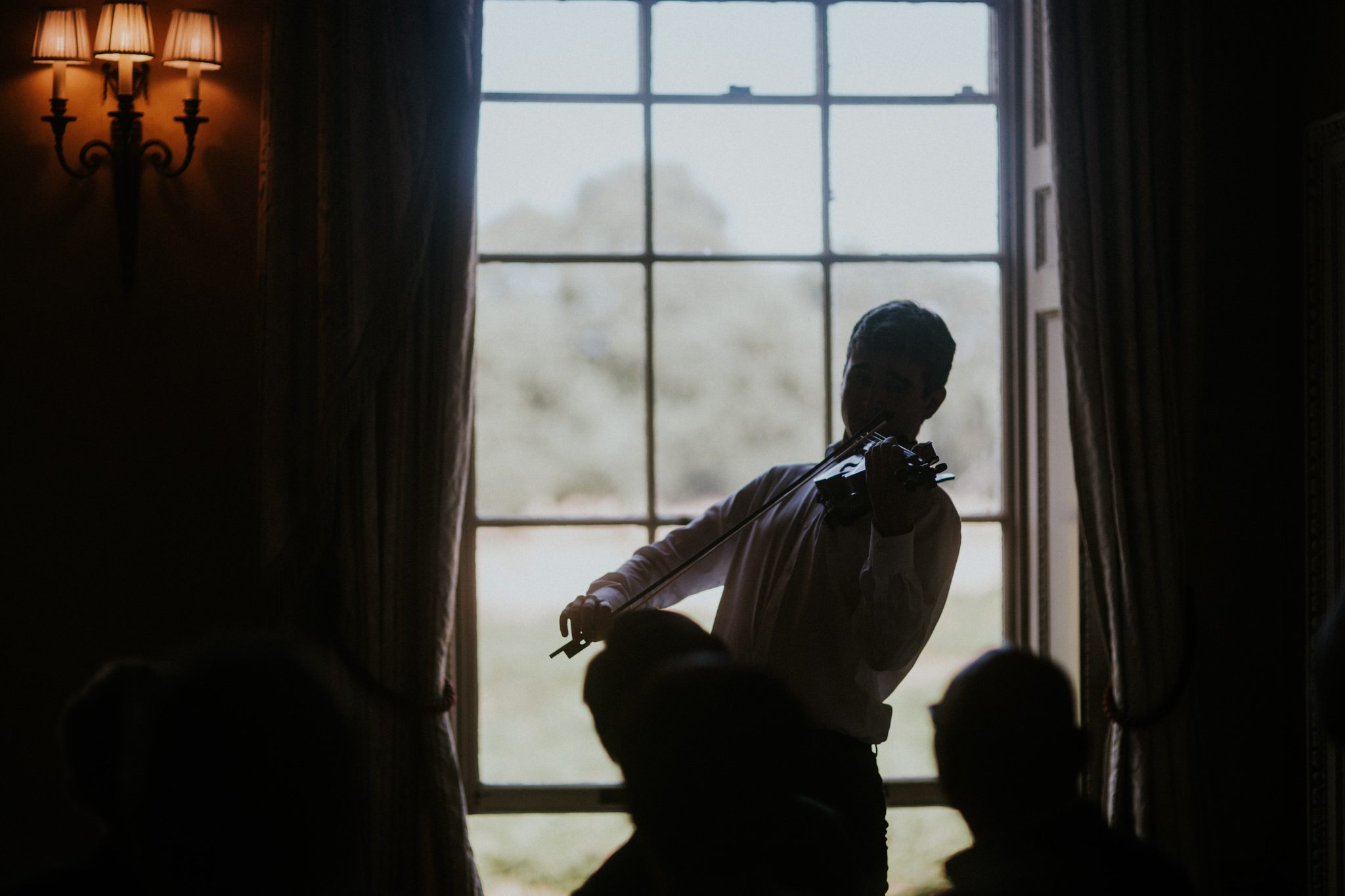 A violinist plays by the window during a wedding at Hampton Court House