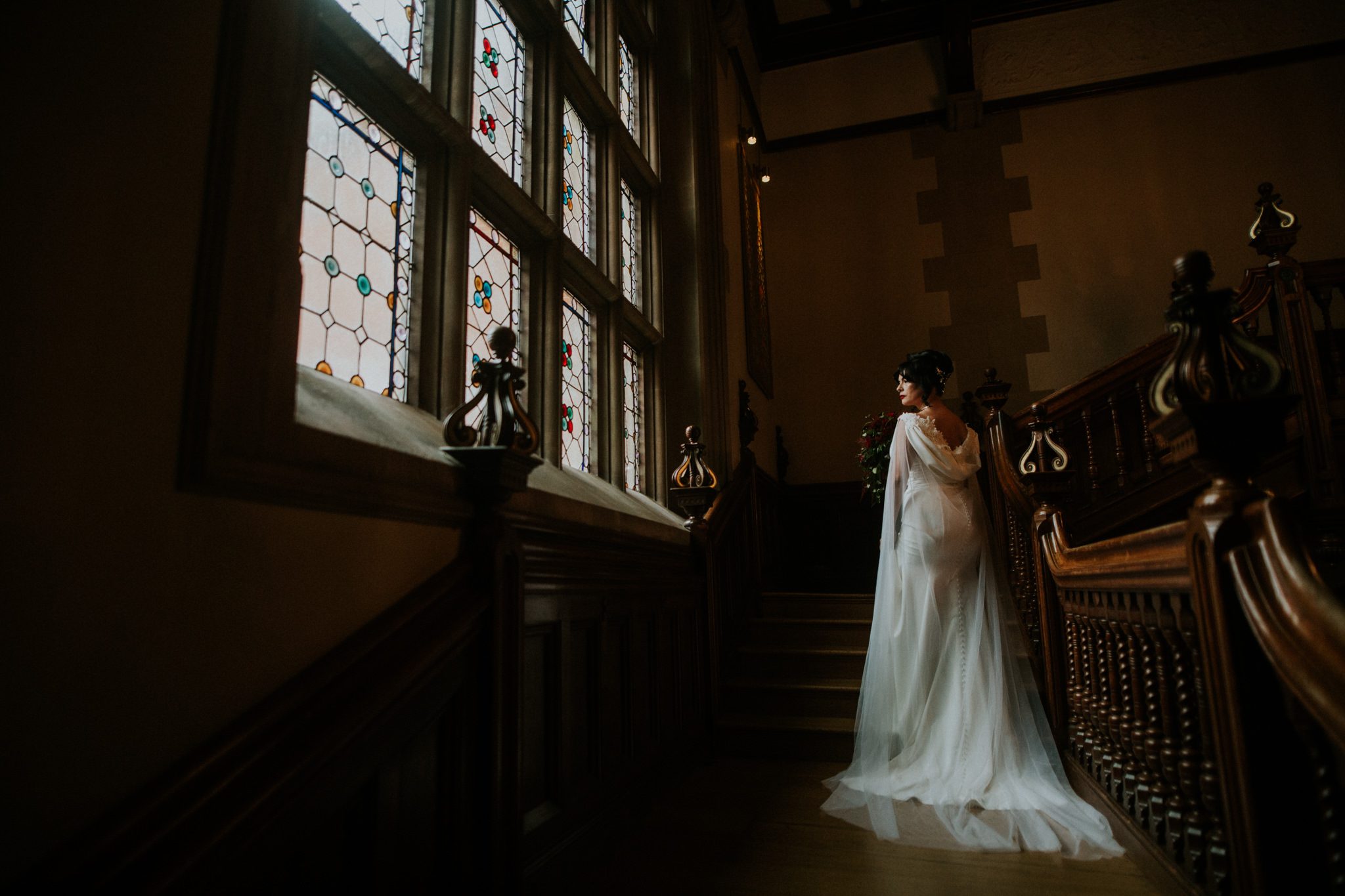 A bride gazes towards a winow on some grand stairs at Penderley Manor