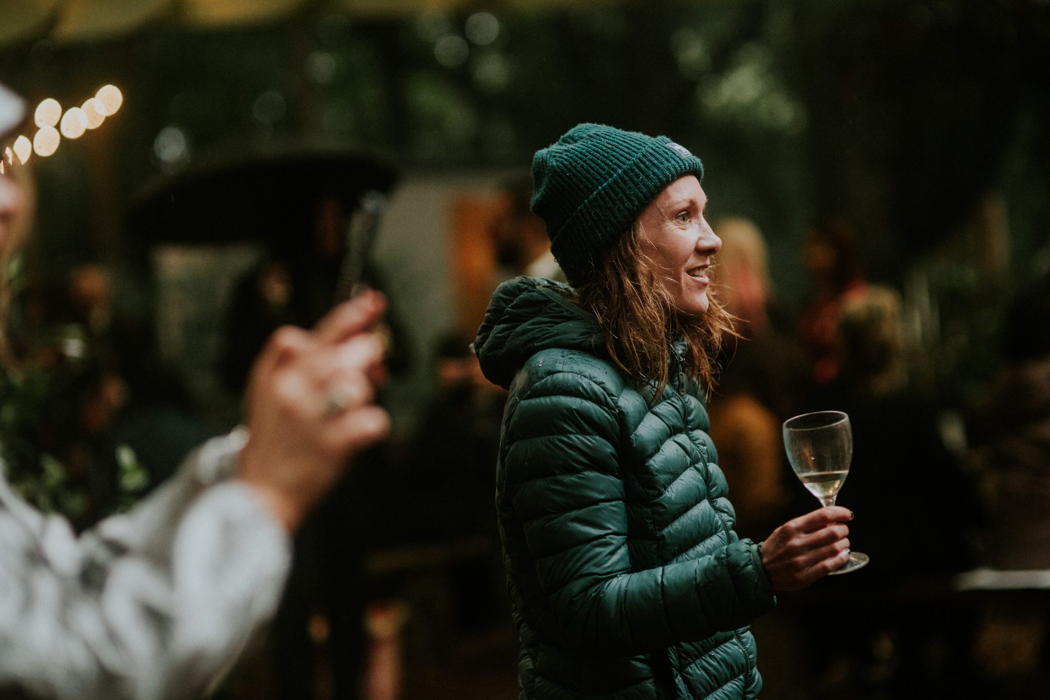 A wedding guest drinks wine in the rain