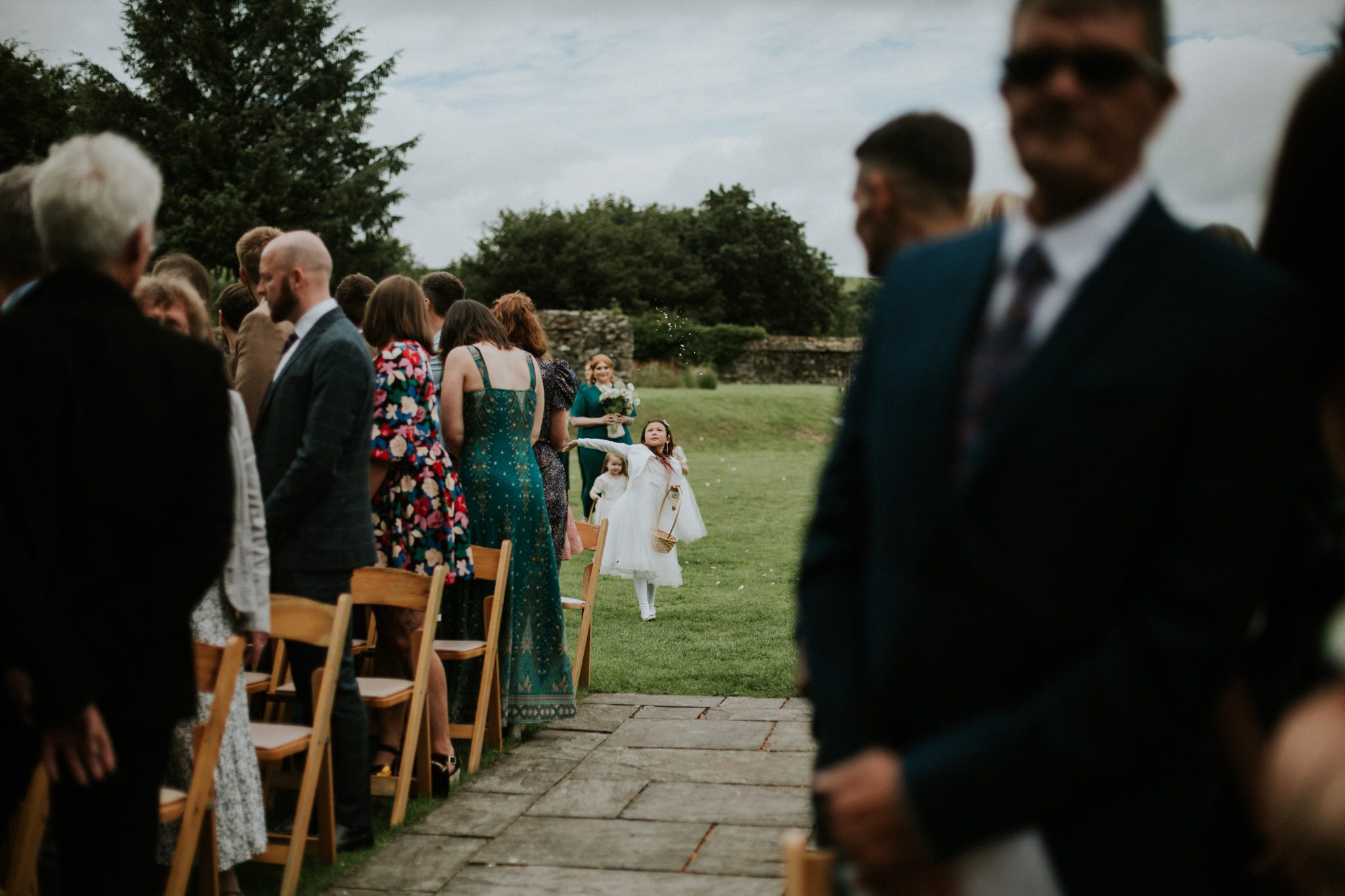Young bridesmaid throws petals at a wedding ceremony at Trevenna Barns in Cornwall