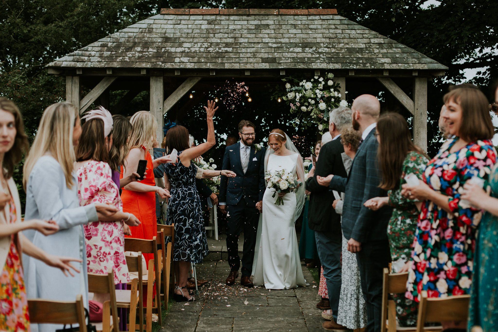 Wedding guests throw confetti for the bride and groom at a wedding ceremony at Trevenna Barns in Cornwall