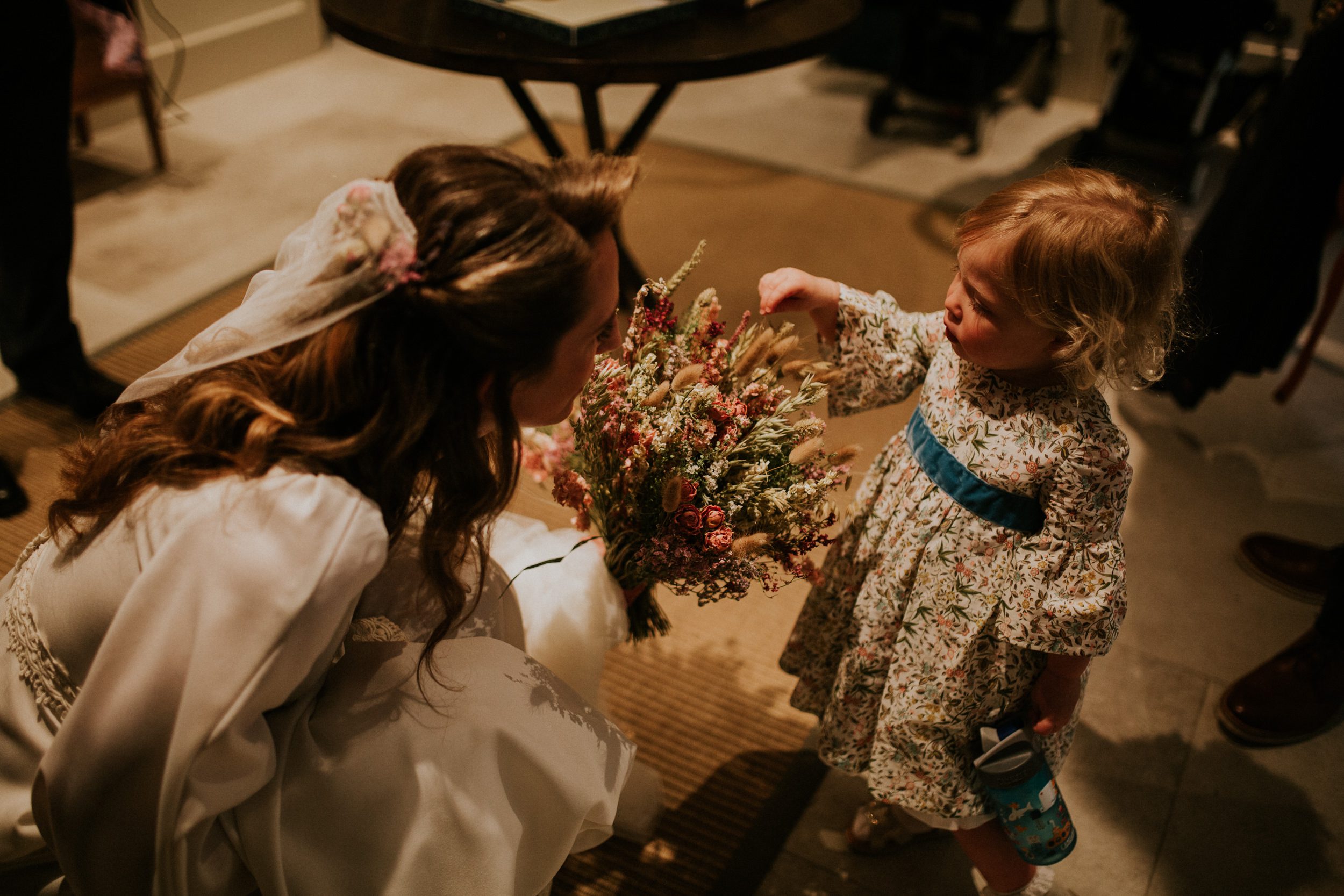 A bride shows her daughter her wedding bouquet before her wedding at St Enodoc in Cornwall