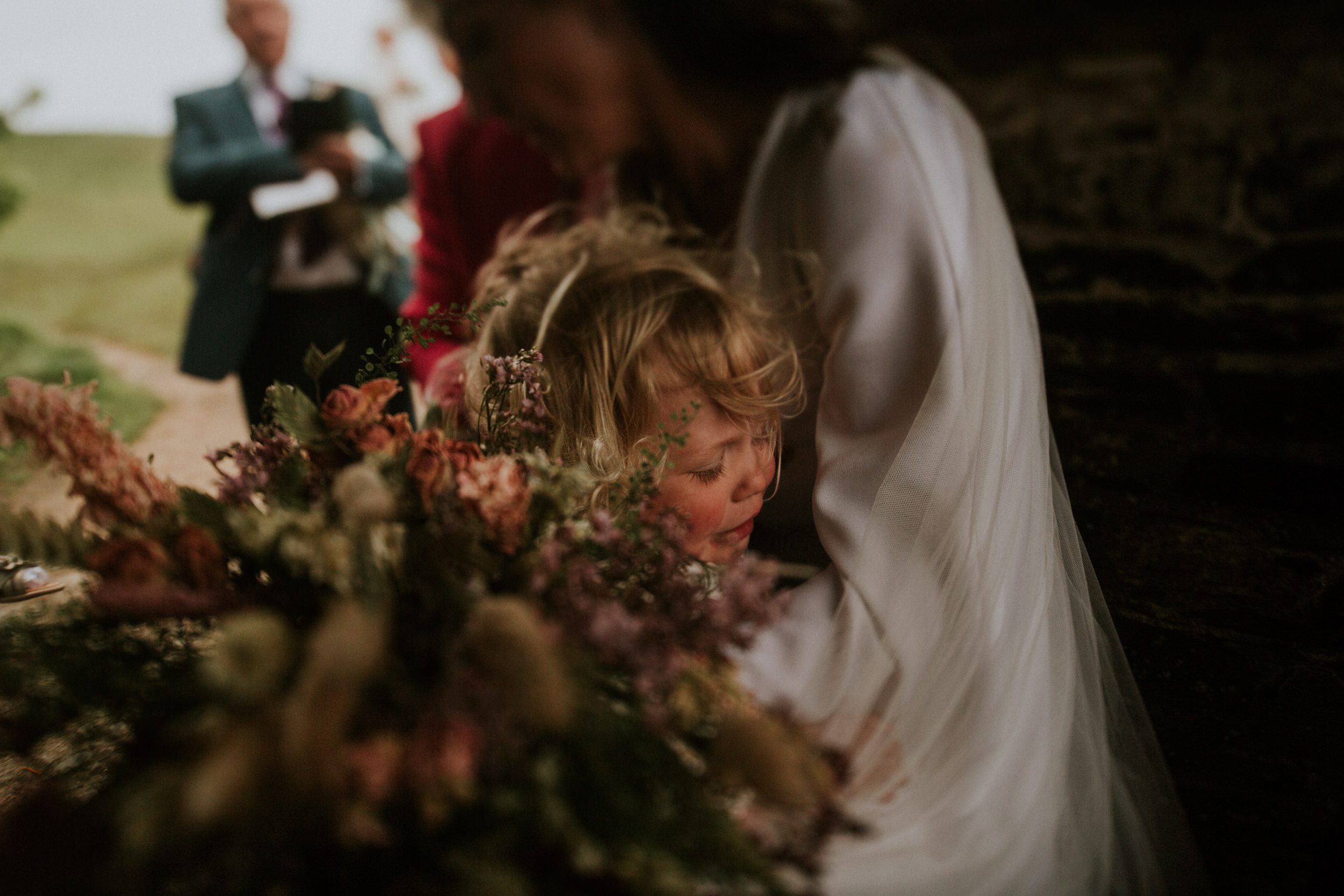 A bride carries har daughter in her arms after her wedding at St Enodoc in Cornwall