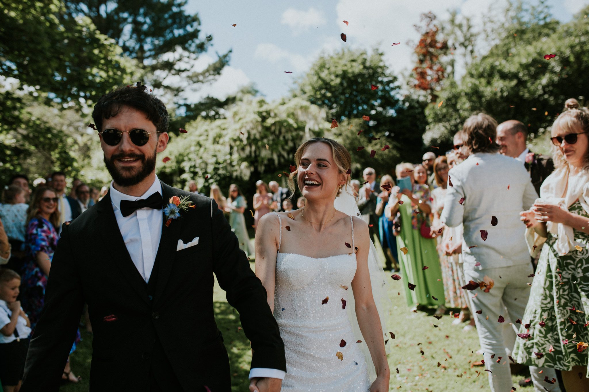 A bride and groom walk through cofewtti thrown by well wishers after their wedding at Hayne Devon