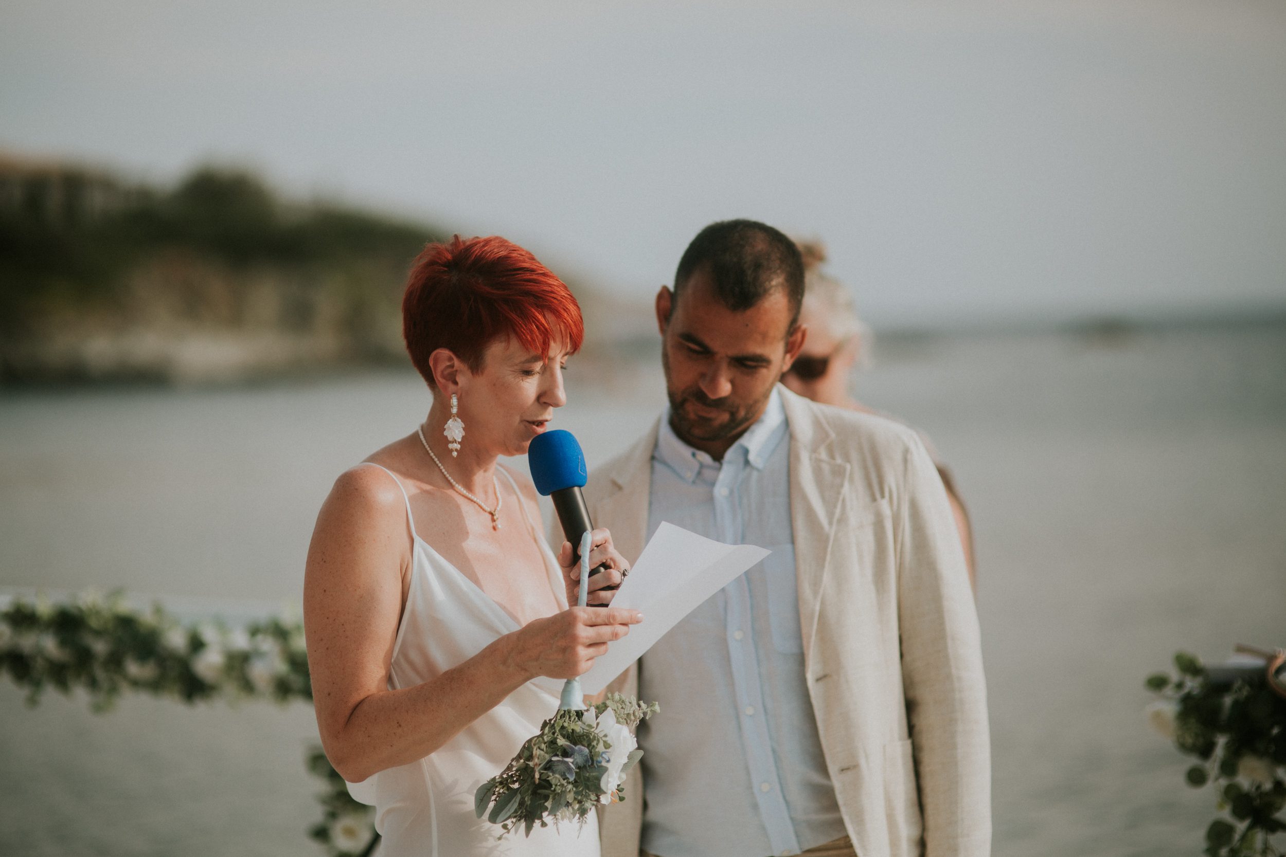 A bride reads her vows to her groom at her wedding on the Athenian Coast in Greece