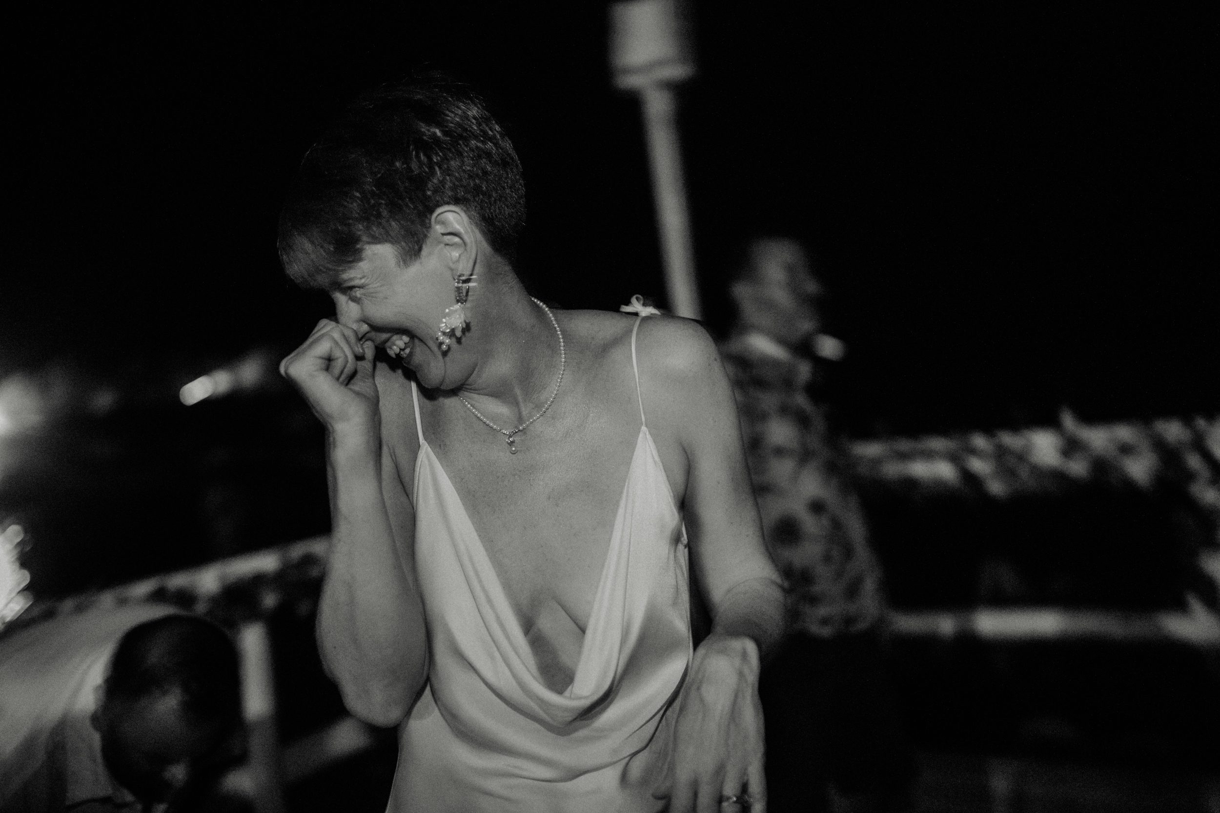 A bride laughs on the dance floor at her wedding on the Athenian Coast in Greece