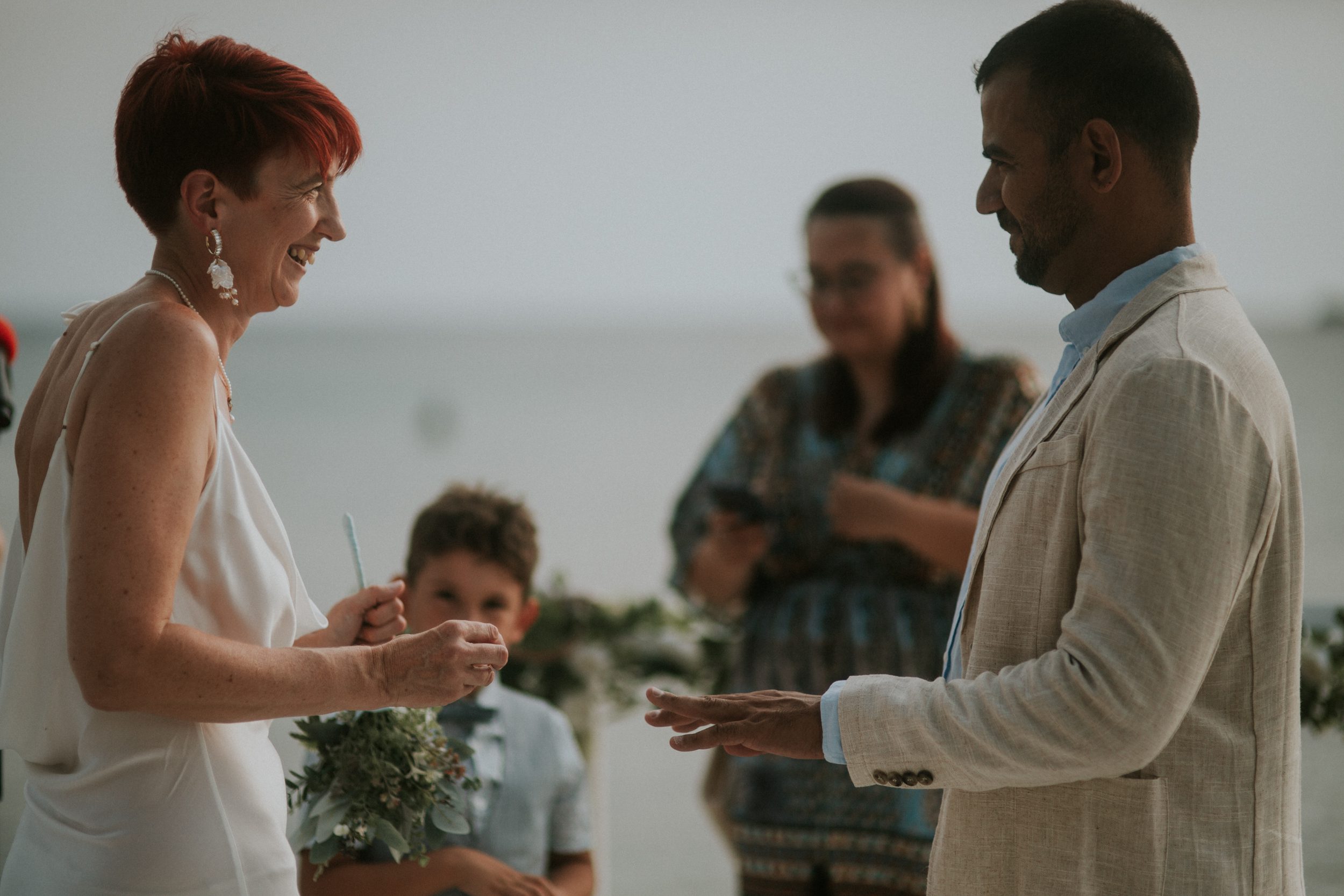A bride and groom exchange wedding rings at their wedding on the Athenian Coast in Greece