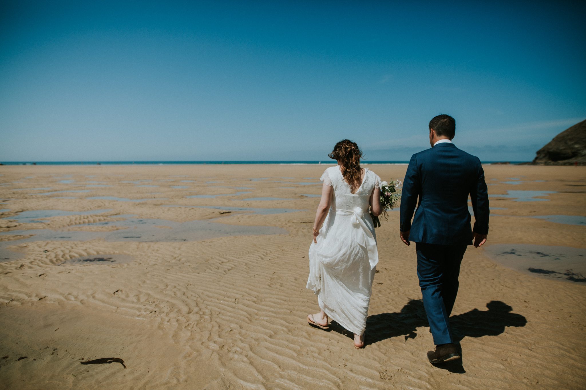 A bride and groom take a walk on the beach after their wedding ceremony at The Scarlet in Cornwall