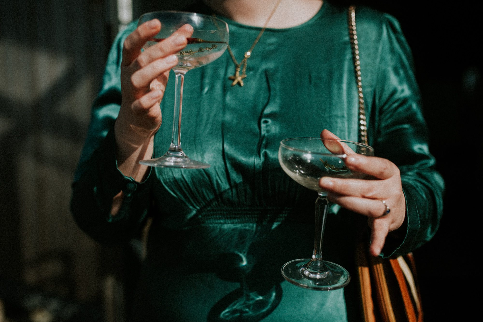 A wedding guest holds two glasses at a wedding reception at Above the Bay in Falmouth