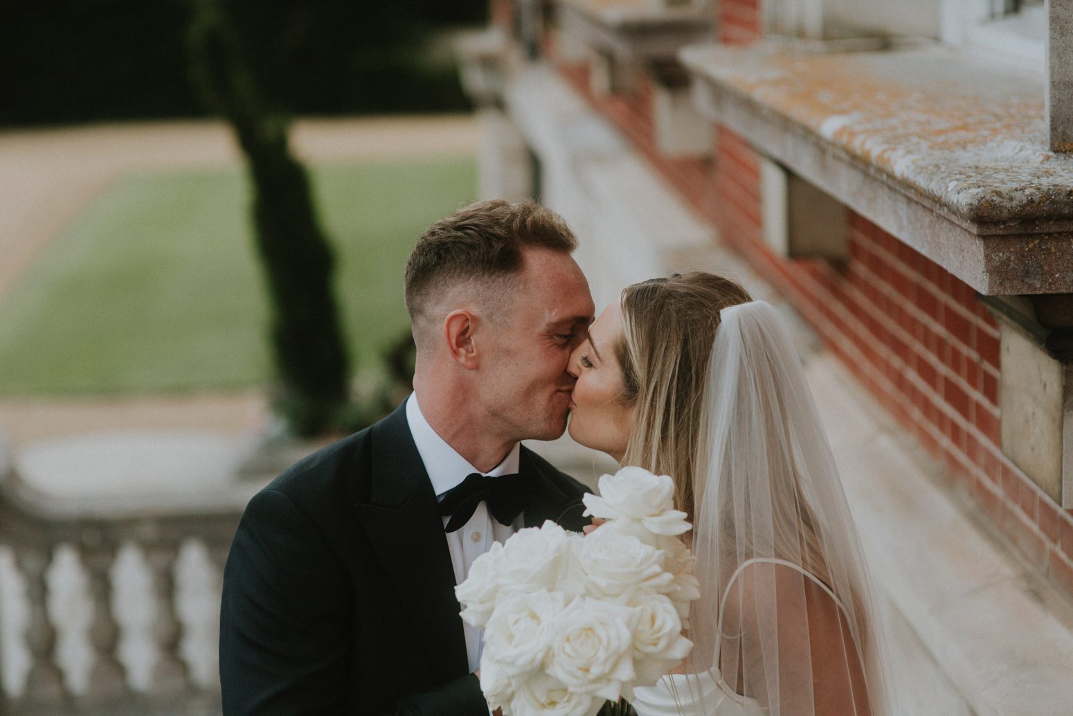 A newly married bride and groom share a quiet kiss at their wedding at Bryanston School in Dorset