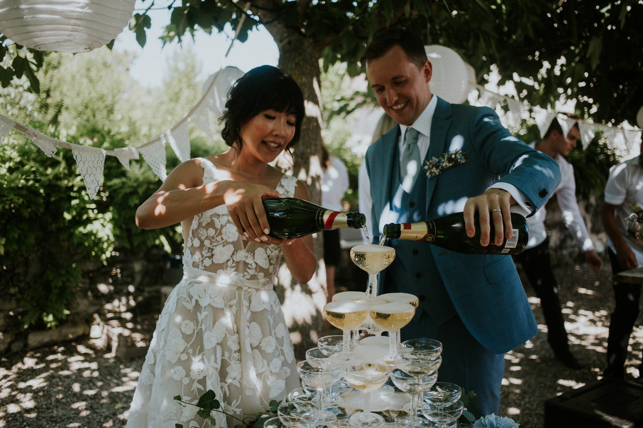 A newly married couple pour into a champagne tower at the reception of their wedding at the wedding venue Chateau St Paul, Marry Me In France