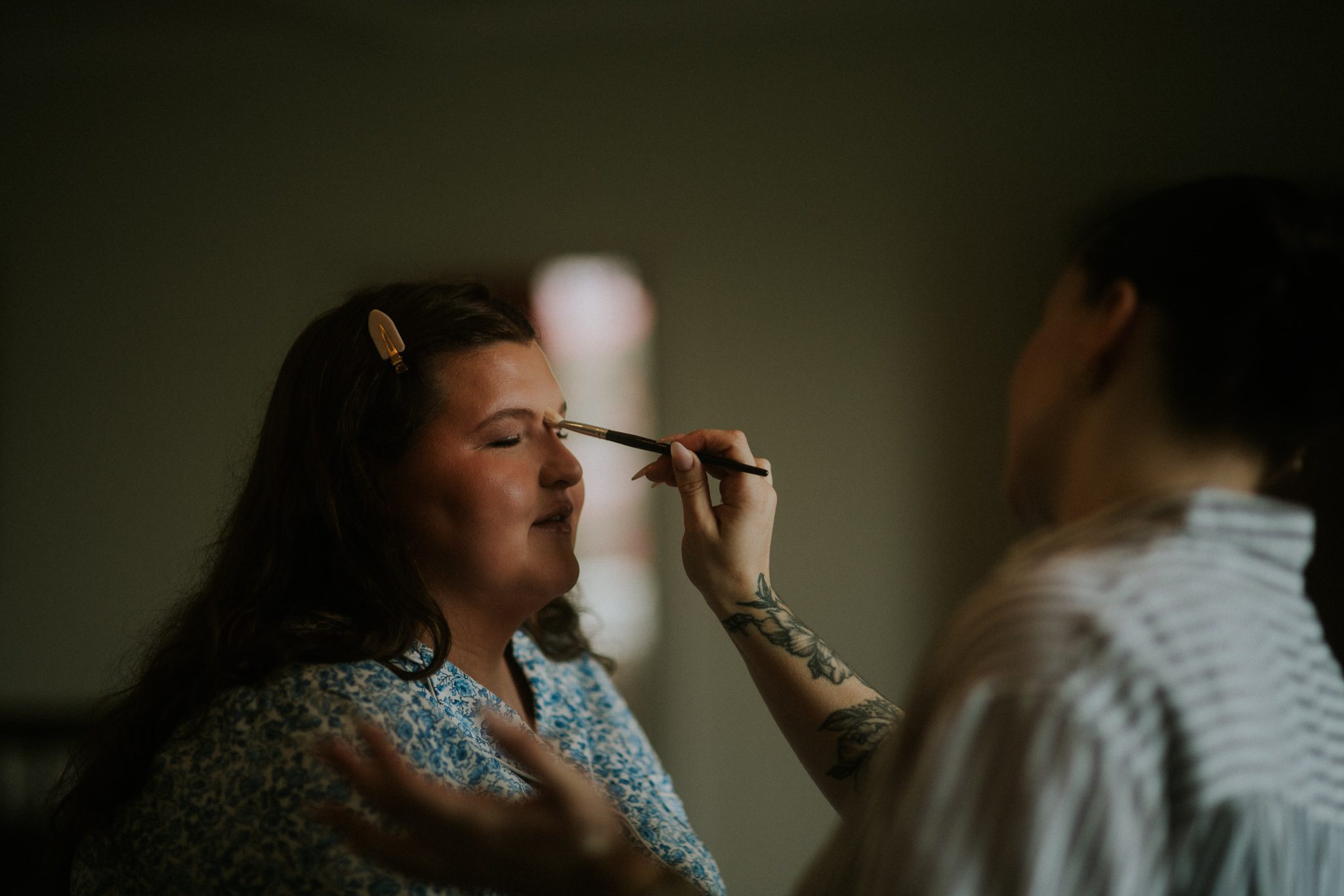 A bride is attended to by a make up artist before her wedding at Scorrier House in Cornwall