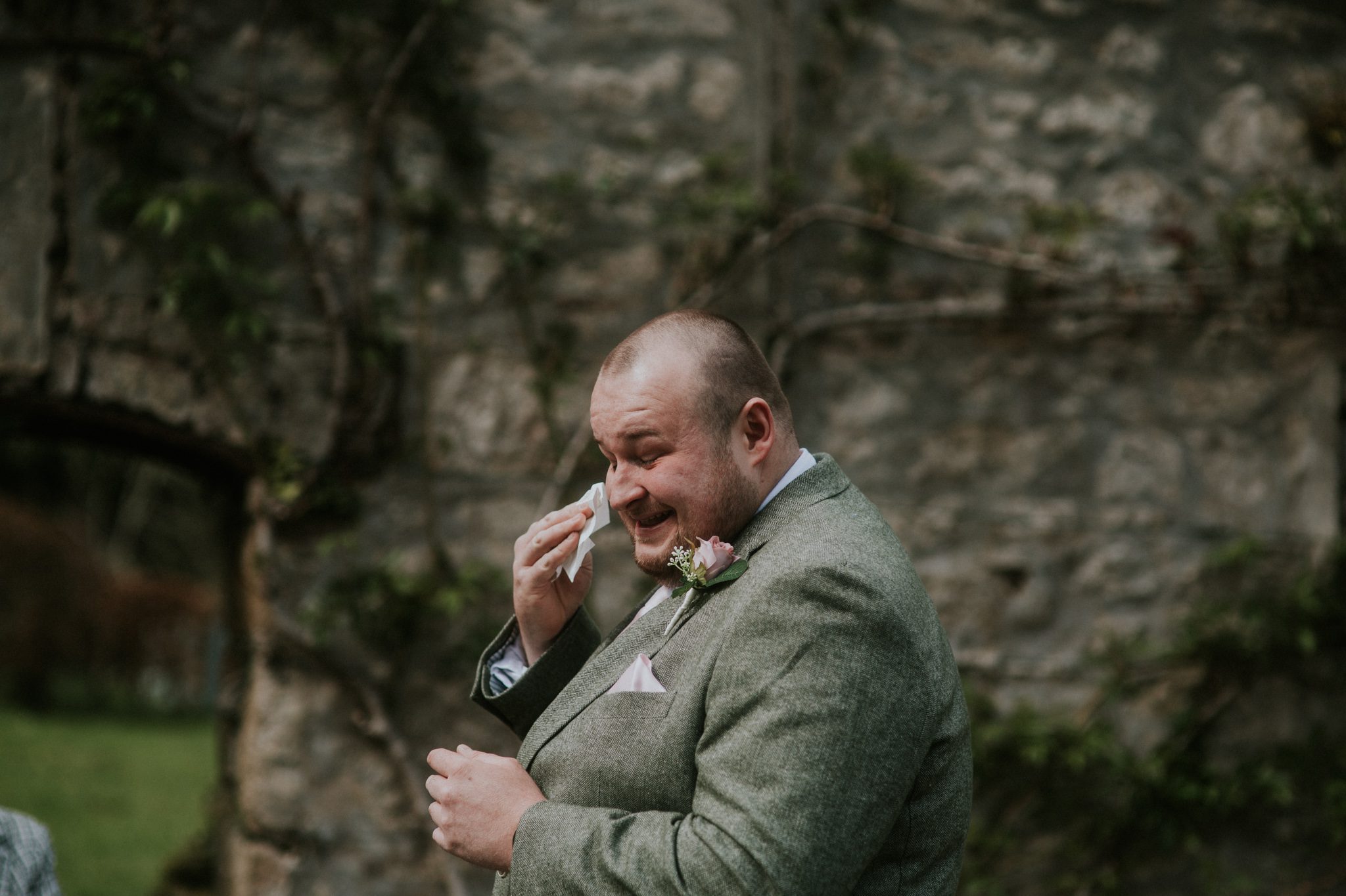 A groom wipes a tear from his eye during the wedding ceremony at Scorrier House in Cornwall