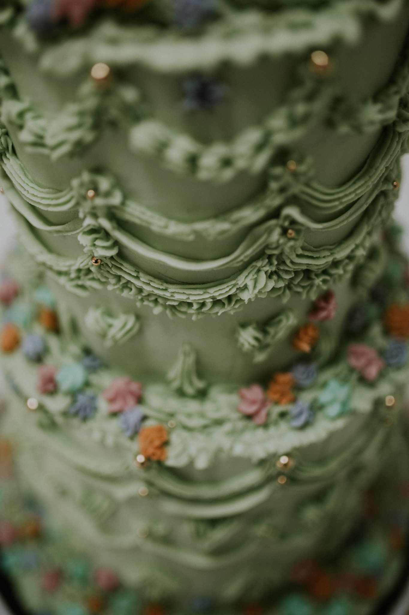 A close up detail of a green Lambeth style wedding cake at Scorrier House in Cornwall